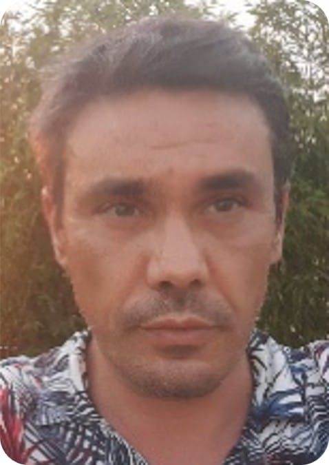 A man with short dark hair and a trimmed beard looks at the camera outdoors, greenery in the background. He is wearing a patterned shirt, reflecting his passion for ecophysiology and climate-resilient agriculture.