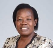 A woman with short, dark hair is wearing a patterned top and looking directly at the camera against a plain background, embodying the spirit of climate-resilient agriculture and innovation in crop modelling.